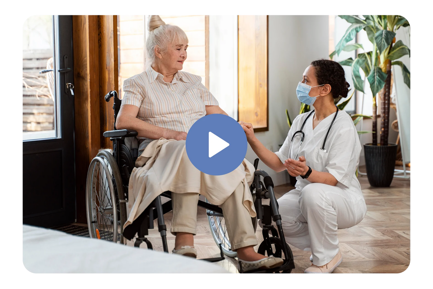 Woman in a wheelchair being assisted by a healthcare professional in a home setting.