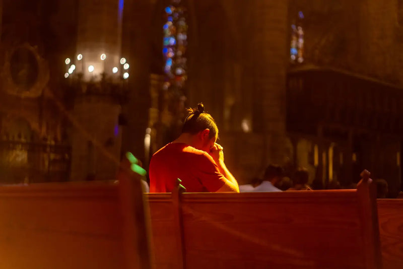 a man sits quietly on a wooden pew